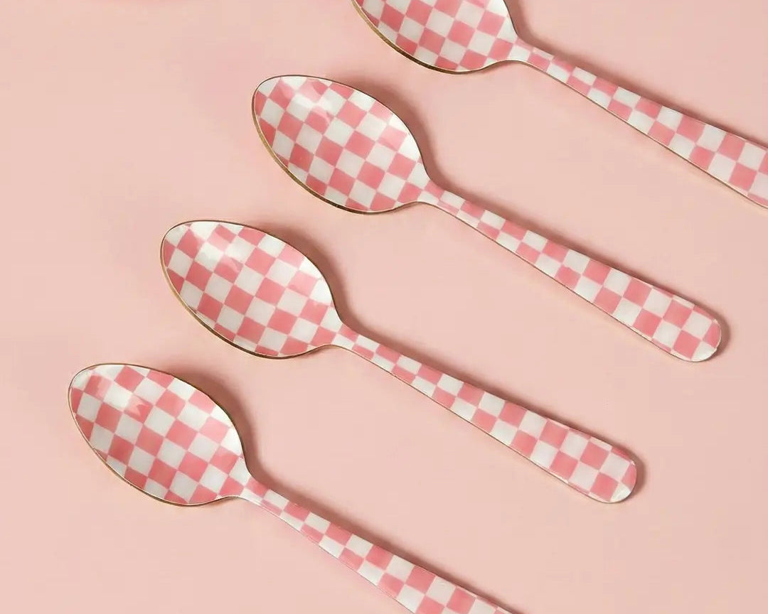 Set of four pink and white checkered spoons on a pink background